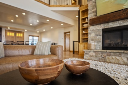 Relax in your spacious living area with soaring ceilings, a stone fireplace, and warm wood accents throughout. Sink into the leather sofa and enjoy the open, inviting ambiance.