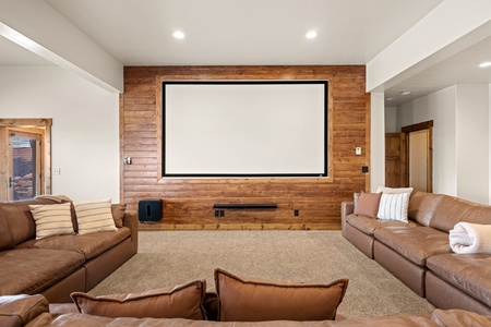 Sink into plush leather seating in your private home theater, where a large projection screen and warm wood accent wall set the stage for unforgettable movie nights.