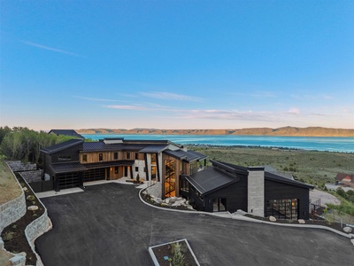 Modern architectural estate set against a stunning lake and mountain backdrop, offering a serene natural setting for an unforgettable getaway.
