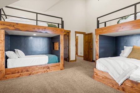 Two custom bunk beds crafted from rich wood and accented with slate-blue walls create a cozy, space-smart retreat for the whole crew. Crisp white bedding and thoughtful design make bedtime feel effortless.