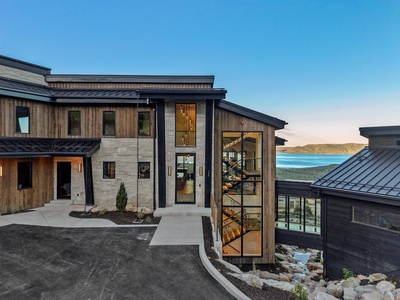 Modern mountain architecture with wood and stone finishes welcomes guests, while stunning turquoise lake views frame this upscale property's peaceful hillside setting.