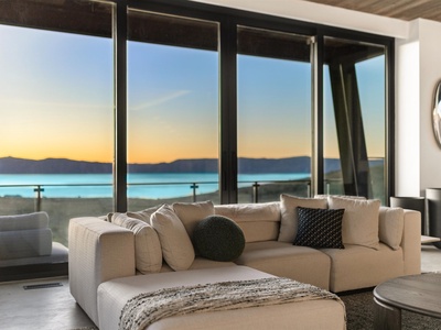 Unwind in your serene living room, where floor-to-ceiling windows frame a stunning lake and mountain sunset—perfect for your peaceful evenings at the end of each day.
