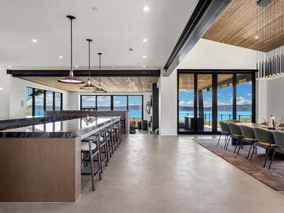 Stunning open-concept space with soaring ceilings, warm wood accents, and floor-to-ceiling windows framing breathtaking turquoise ocean vistas—your perfect gathering spot for memorable island meals.