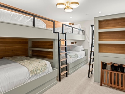 Your group will love this thoughtfully designed bunk room with plush white linens, warm wood accents, and a stylish modern light fixture, perfect for restful nights together.
