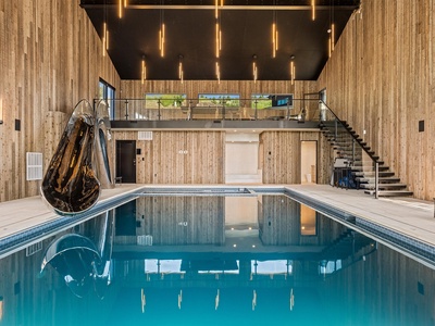 Dive into your private indoor pool beneath soaring ceilings and modern lighting—a luxurious space where relaxation meets contemporary design, complete with water slide and open loft views.