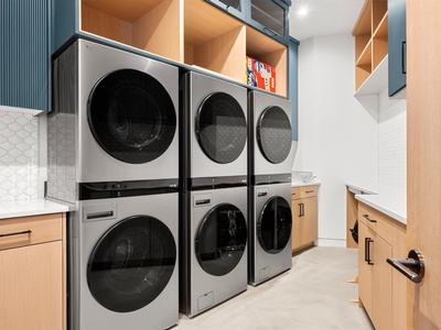 Your laundry days just got easier with stacked washers and dryers lined up for your convenience, plus plenty of warm wood shelving to keep your supplies organized and within reach.
