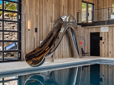 An eye-catching stainless steel slide curves down to your private indoor pool—fun and relaxation await in this unique, modern retreat.