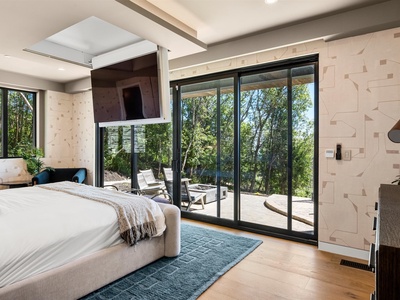 Step into your tranquil bedroom retreat featuring sleek modern design, textured wood accent walls, and floor-to-ceiling glass doors opening to your private terrace surrounded by lush trees.