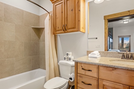 Step into a fresh, well-appointed bathroom with warm wood cabinetry and a soothing neutral palette. Crisp linens and thoughtful details await your arrival.