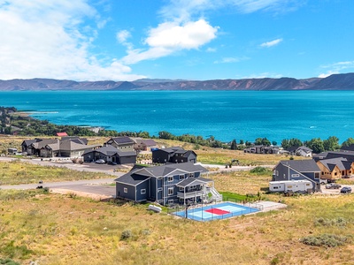 Stunning lakefront property with private basketball court nestled among modern homes near pristine mountain-ringed waters.