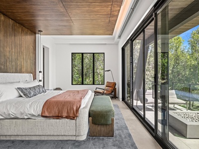 Drift off in your serene bedroom where natural wood tones meet bright white walls. Step through sliding glass doors onto your private balcony and wake up to lush forest views framing every morning.