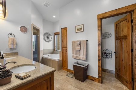 Averon Lodge - Bear Lake Luxury Rentals. Unwind in your spacious master bathroom with rustic wooden accents, granite countertops, and a relaxing soaking tub for ultimate comfort.