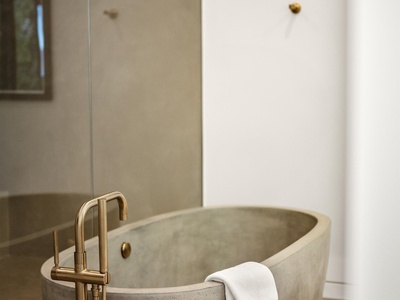 Slip into your private sanctuary with a sculptural concrete tub and elegant brass fixtures—your personal spa awaits after a day of exploring.
