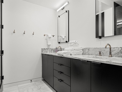 Step into your spa-like bathroom with dual sinks, marble countertops, and plush towels waiting to wrap you in comfort after a refreshing shower.