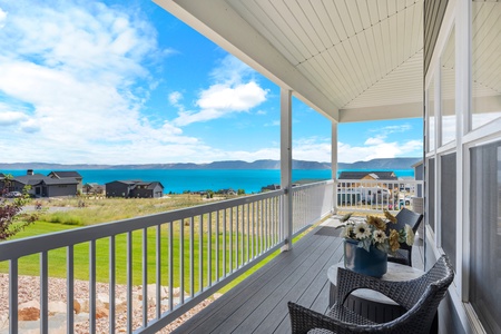 Covered balcony with stunning lake and mountain views, featuring comfortable outdoor seating for relaxing moments.
