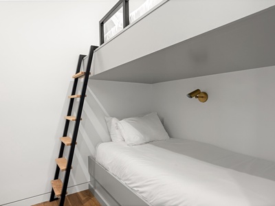 Cozy built-in bunks with crisp white linens invite restful sleep, while the sleek ladder and reading light add modern comfort to your retreat.