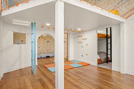 An imaginative indoor play space with climbing walls, a rope cargo net overhead, and cozy bunk nooks—perfect for your kids to explore, climb, and dream.