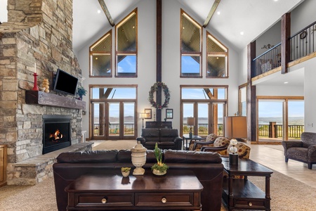 Averon Lodge - Bear Lake Luxury Rentals. Unwind in this stunning great room where soaring ceilings and panoramic windows frame breathtaking views while you cozy up by the stone fireplace.