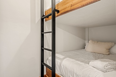 Your cozy bunk room awaits with crisp white linens, plush towels, and warm wood accents—perfect for a restful retreat after exploring.