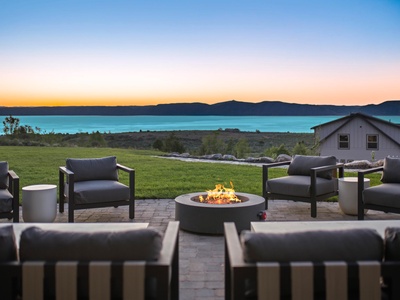 Stunning lakeside patio with modern fire pit, mountain silhouettes, and twilight sky providing a peaceful retreat for gathering and relaxation.