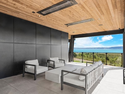 Relax in your private lounge with floor-to-ceiling windows framing sweeping lake and mountain views. Sink into modern seating under warm wood ceilings and soak in the serene landscape beyond.