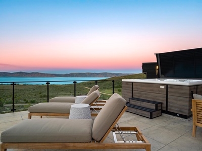 Twilight paints the sky in pastels over turquoise waters while your private terrace awaits—sink into plush loungers, soak in the hot tub, and let the sweeping lake and mountain views melt away the everyday.