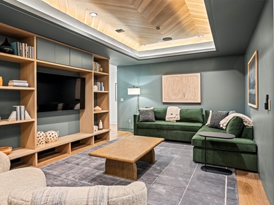 Settle into plush green sofas beneath stunning wood-paneled ceilings, where you can unwind with your favorite show or curl up with a book from the built-in shelves.