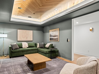 Sink into the plush green sectional and let your gaze drift up to the striking herringbone wood ceiling. This cozy retreat invites you to unwind in style.