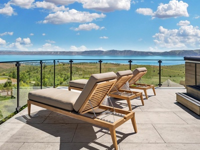 This expansive terrace overlooks stunning turquoise lake waters and distant mountains, framed by lush green countryside—an ideal backdrop for your arrival and stay.