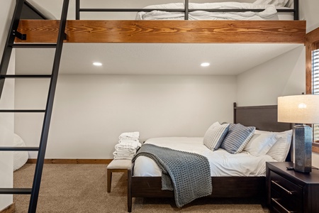 Your cozy bedroom features a plush bed dressed in soft linens and a lofted bunk above for extra sleeping space—perfect for families or groups seeking mountain comfort.