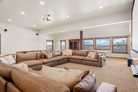 Sink into plush leather sectionals and unwind in your spacious gathering room, where natural light streams through expansive windows and everyone finds their perfect spot to relax.