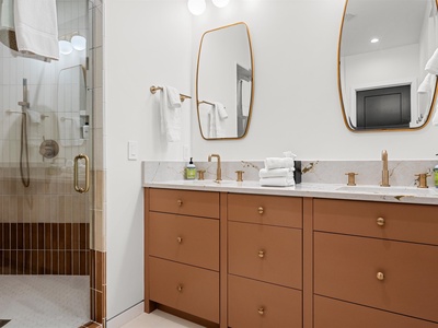 Step into your spa-like bathroom with a spacious walk-in shower, double vanity with plenty of storage, and elegant gold-toned fixtures that create a warm, luxurious retreat.