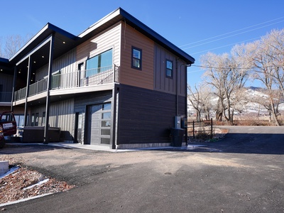 Modern two-story building with mountain views and convenient parking, situated in a scenic winter landscape.
