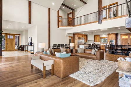 Soaring ceilings and warm wood beams frame your spacious gathering area, where leather seating invites you to unwind while the open kitchen and upper-level loft keep everyone connected.