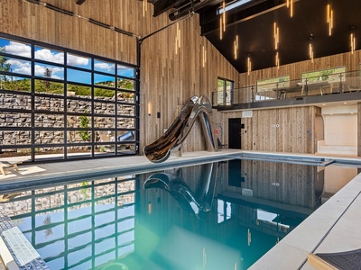 An indoor pool awaits your arrival, complete with a thrilling waterslide and contemporary design. Floor-to-ceiling windows bathe the space in natural light while warm wood accents create an inviting atmosphere for your stay.