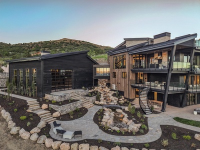 Modern mountain retreat nestled against scenic hillside terrain, featuring multi-level architecture with contemporary design and thoughtfully landscaped outdoor spaces.