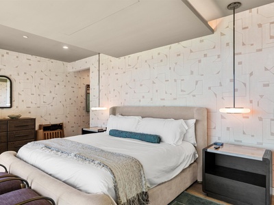 Sink into crisp linens and modern comfort with textured accent walls and warm ambient lighting to frame your restful retreat.