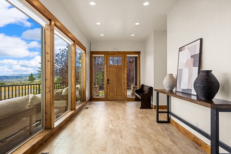 Step into a bright, welcoming entryway with warm wood accents and sweeping views of the rolling landscape beyond. Natural light pours through floor-to-ceiling windows, creating an inviting first impression that sets the tone for your entire stay.