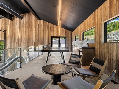 Step into a sophisticated common area where modern design meets natural warmth. Relax in stylish seating while enjoying the bright, airy space and scenic hillside views through floor-to-ceiling windows.