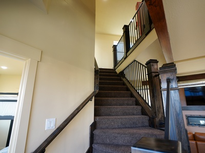 Beautiful carpeted staircase with rich wood railings leads you to your upstairs retreat, creating an elegant transition between floors.