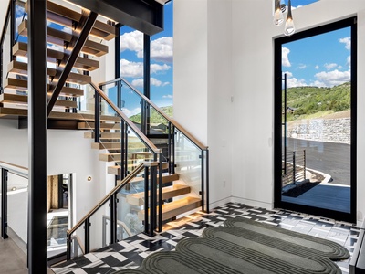 Step into a bright, modern entryway where sleek design meets stunning natural surroundings. Sunlight pours through expansive windows, framing peaceful hillside views that welcome you home.
