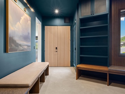 A sophisticated entryway welcomes you with rich teal walls, elegant artwork, and warm wood furnishings. Generous storage and built-in shelving keep everything tidy for your stay.