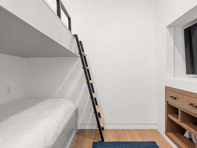 Maximize your space in this modern sleeping area with built-in bunks and a charming ladder, perfect for kids or extra guests seeking cozy comfort.