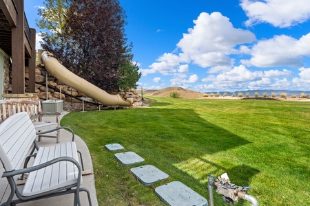 Expansive backyard with lush green lawn, mountain views, and a fun water slide for the kids. Picture lazy summer days spent relaxing on the patio or splashing in the sun.