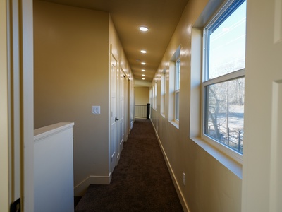 A welcoming hallway leads you to your room, with natural light streaming through windows and warm lighting guiding your way.