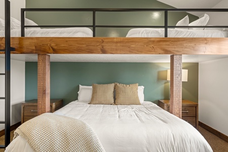 You'll love the clever bunk bed design with cozy bedding, perfect for maximizing space while keeping everyone comfortable. The warm wood tones and calming sage accent wall create a peaceful retreat.