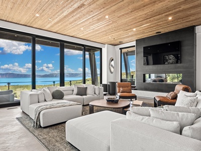 Sink into plush seating beneath warm wood ceilings while drinking in sweeping lake and mountain views through floor-to-ceiling windows—your perfect retreat awaits.