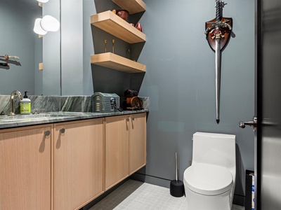 This sleek bathroom features calming blue-gray walls, a modern vanity with marbled countertop, and playful pirate-themed décor—making your stay feel both stylish and fun.