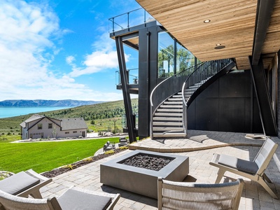 Stunning modern patio showcases an architectural spiral staircase, sleek fire pit, and breathtaking lake and mountain panoramas—an extraordinary space for outdoor relaxation and entertaining.
