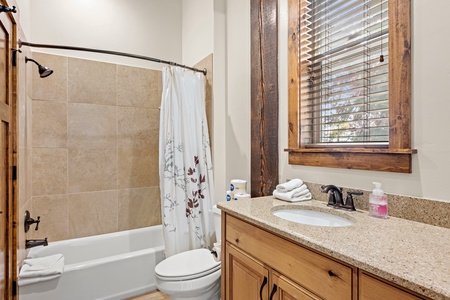 Freshen up in your private bathroom featuring a granite vanity, warm wood accents, and a soothing tub-shower combo—everything you need to start or end your day feeling refreshed.